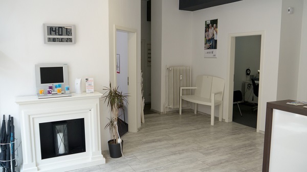 Modernes Wartezimmer in einer Arztpraxis mit Sitzbank, Pflanze und Informationsmaterial.